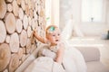 Little blue-eyed girl blond in a white tulle dress with a decoration on her head playing and rejoicing on a beige sofa in a room w Royalty Free Stock Photo