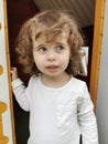 Little blue-eyed girl looking suspiciously to the side leaving a doll house Royalty Free Stock Photo