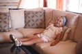 Little blue-eyed girl sits on a large rattan sofa Royalty Free Stock Photo