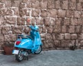 Little blue moped standing against an old stone wall