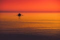 little boat in a sea red orange sky at sunset