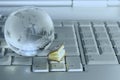 Little book and glass globe on laptop keyboard.