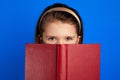 Little book reader hides behind textbook, has joyful expression