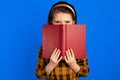 Little book reader hides behind textbook, has joyful expression