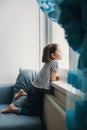 Little bored girl sitting at home and looking at the window Royalty Free Stock Photo