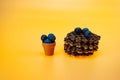 Little bowl with fresh blueberries and Belgian waffles with chocolate on yellow background.