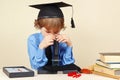 Little boy in academic hat looking through microscope at his desk Royalty Free Stock Photo