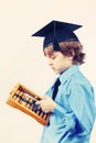 Little boy in academic hat with old abacus on light background, gently toned