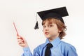Little boy in academic hat with pencil on white background