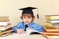 Little boy in academic hat writing pen in notebook among the old books Royalty Free Stock Photo