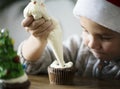 Little boy adding icing on a cupcake