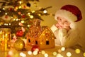 Little boy admiring of sweet homemade gingerbread house decorated candies and glazed. Gingerbread house is standing on table near