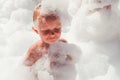 Little boy in airy foam on a dance party floor. Foamy children disco party Royalty Free Stock Photo