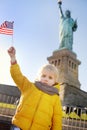 Little boy with American flag on the background of the statue of liberty in the same pose. Royalty Free Stock Photo