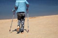 A little boy with Autism, Asperger syndrome on crutches after breaking his leg walks on the beach.