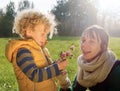 Little boy in autumn clothes gives his mom a flower, close-up Royalty Free Stock Photo