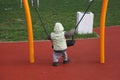 Little boy in autumn jacket swinging on swing Royalty Free Stock Photo