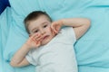 Little boy awakes in his bed. Toddler in white shirt