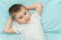 Little boy awakes in his bed. Toddler in white shirt