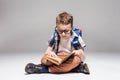 Little boy with backpack reading book in yoga pose Royalty Free Stock Photo