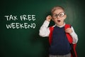 Boy with backpack and text TAX FREE WEEKEND written on chalkboard Royalty Free Stock Photo