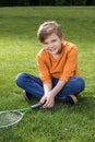 Little boy with badminton racquet sitting on grass Royalty Free Stock Photo