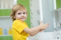 Little boy in a bathroom washes hand with soap