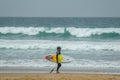 Little boy at the beach with yellow surfboard on the Atlantic Ocean with waves