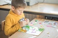 Little boy being creative making homemade do it yourself  dinosaur mosaic. Supporting creativity, learning by doing, learning Royalty Free Stock Photo