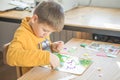 Little boy being creative making homemade do it yourself  dinosaur mosaic. Supporting creativity, learning by doing, learning Royalty Free Stock Photo