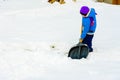 Little boy with big shovel removes snow after a snowstorm Royalty Free Stock Photo