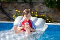 Little boy in a big swimming pool, drinking juice in a hot summer day Royalty Free Stock Photo
