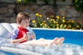 Little boy in a big swimming pool, drinking juice in a hot summe Royalty Free Stock Photo