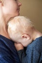 A little boy with blond hair covered his face with hands and sleeps on his mother`s chest Royalty Free Stock Photo