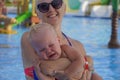 Little boy with blonde hair crying in mom`s arms in a pool