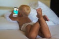 little boy with blonde hair lying on the bed and playing with the phone Royalty Free Stock Photo