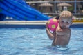 Little boy with blonde hair playing with ball in pool Royalty Free Stock Photo