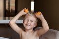 A little boy blonde plays with yellow capsules from kinder surprise, smiles, he is happy