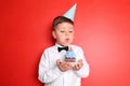 Little boy blowing out candle on birthday cupcake against color background Royalty Free Stock Photo