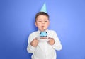 Little boy blowing out candle on birthday cupcake against color background Royalty Free Stock Photo