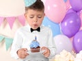 Little boy blowing out candle on birthday cupcake at home Royalty Free Stock Photo