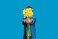 A little boy on a blue background holds a bouquet of beautiful yellow daffodils in his hands. Holiday concept - March 8,