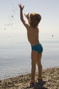 Little boy in blue cowards throws stone up Royalty Free Stock Photo