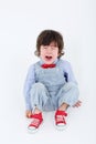 Little boy in blue jumpsuit sits on floor and cries