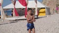 wet little boy in blue shorts freeze and shiver shake on summer beach after swimming during holiday vacation travel to