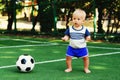 Little boy in blue shorts playing with soccer ball at sports ground. Blonde child in uniform standing at football field with ball Royalty Free Stock Photo