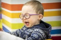 A little  boy in a blue sweater with glasses screams in the playroom Royalty Free Stock Photo