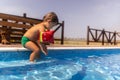 Boy with armbands playing with toys near the pool with clear water on the background of a summer sunset Royalty Free Stock Photo
