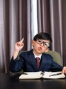 Little boy in business suit write someting on the book and pointing on top