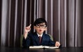 Little boy in business suit write someting on the book and pointing on top